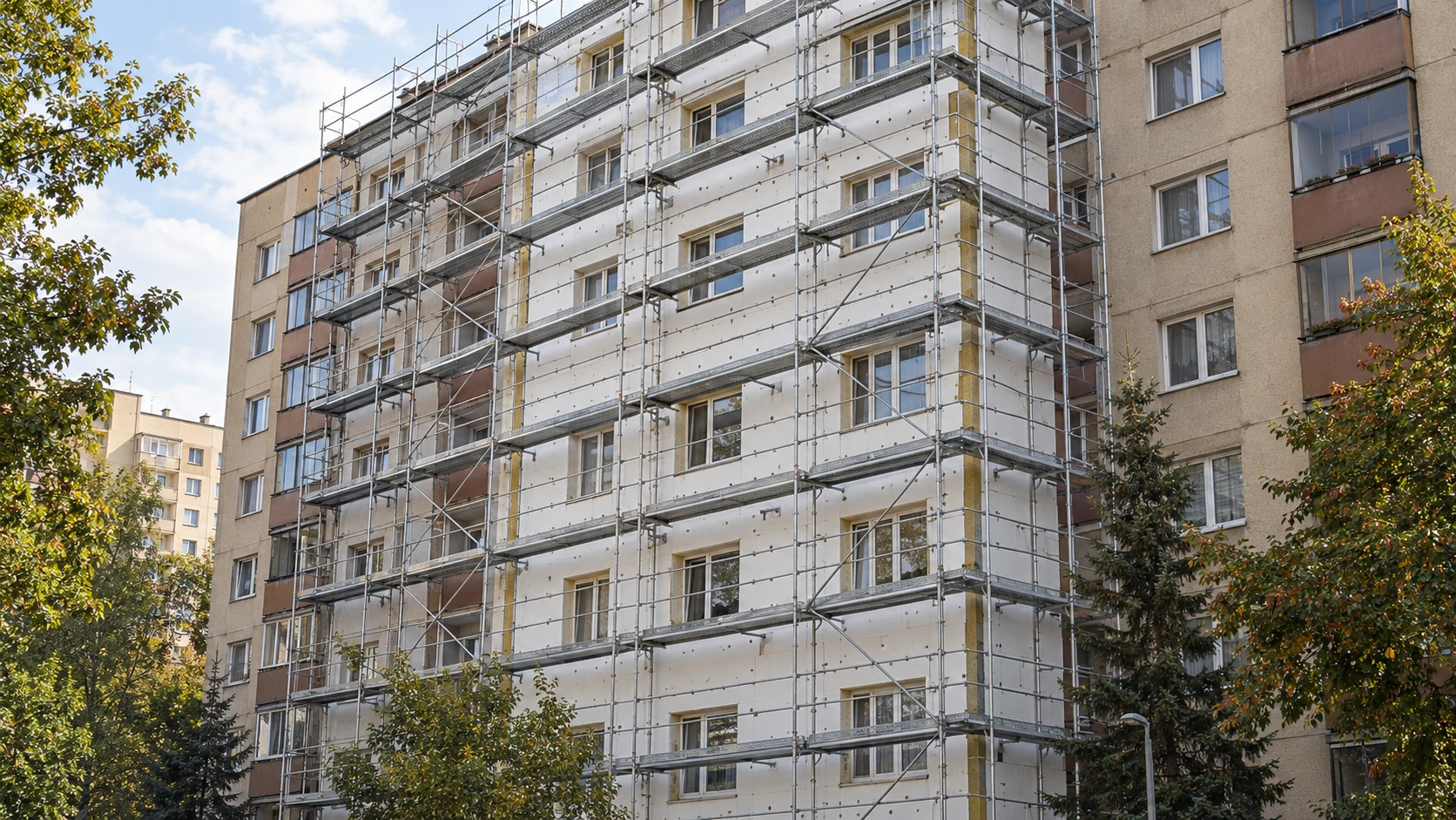 Blok mieszkalny ocieplany białymi płytami styropianowymi na rusztowaniu